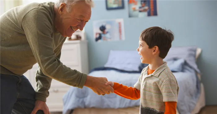 Мальчик и его дедушка, пожимающие друг другу руки