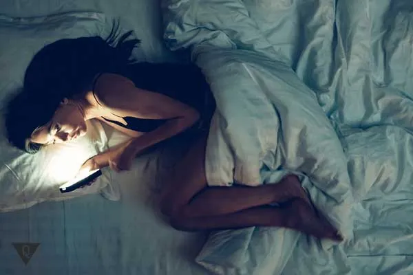 Девушка с телефоном в кровати не знает как войти в режим сна